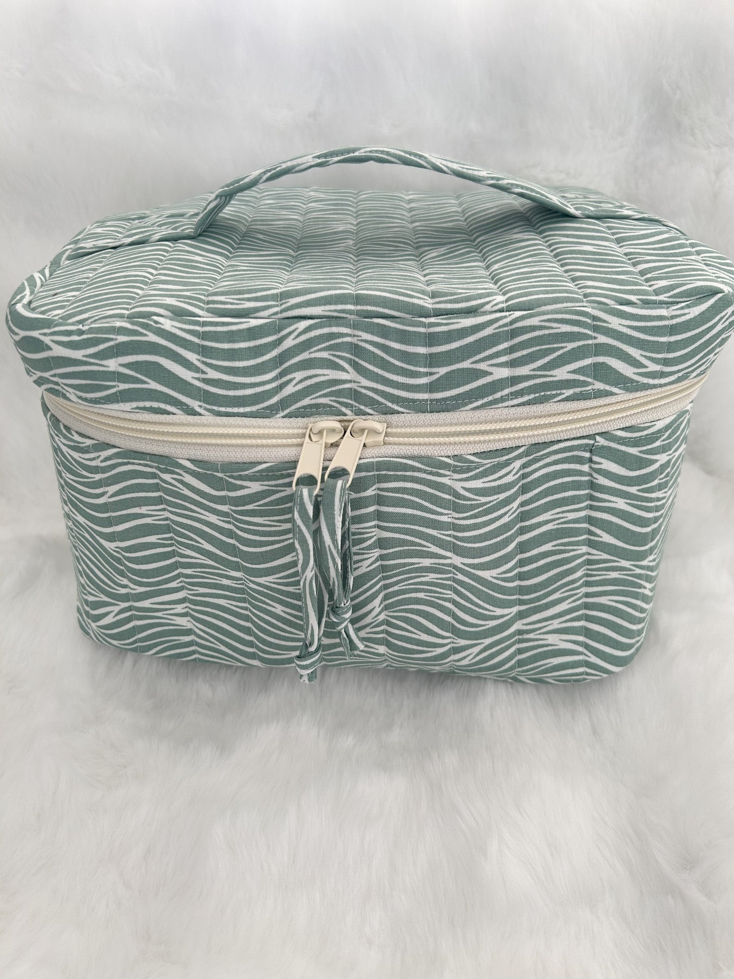 Green wavy patterned train case on a white background