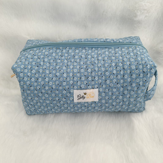 Blue daisy patterned quilted makeup bag with gold flecks and a visible Gilly Bee brand label