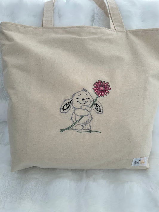 Calico tote bag featuring an embroidered bunny character holding a pink flower